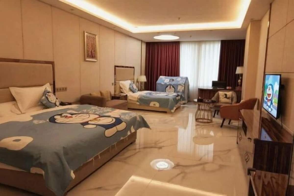 A hotel room with two beds, a TV, a desk, and a chair.