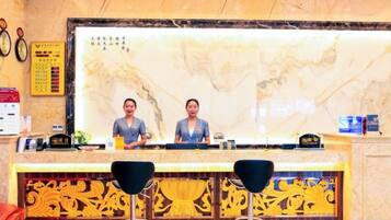 A reception area with a marble counter, two receptionists, and a decorative wall.