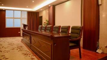 A hotel room with a reception desk, a seating area with chairs, and a large window.