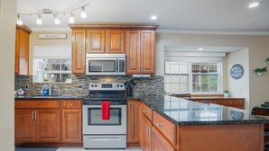 Eine moderne Küche mit Holzschränken, einer Granit Arbeitsplatte, einem Edelstahlbackofen und einer Mikrowelle.