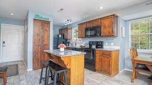 A modern kitchen with wooden cabinets, a granite countertop, and stainless steel appliances. - 2BR Condo | Lake Views | Walk-In Access (Branson)