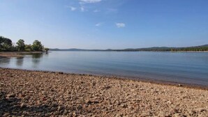 A calm lake with a pebbly shore and distant hills.