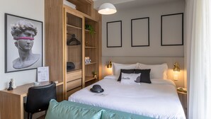 Une chambre d’hôtel comprenant un lit, un bureau, une armoire et une œuvre d’art encadrée accrochée au mur.