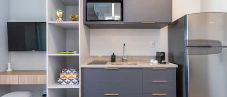 A modern kitchen with a built-in microwave, a stainless steel refrigerator, and a granite countertop.