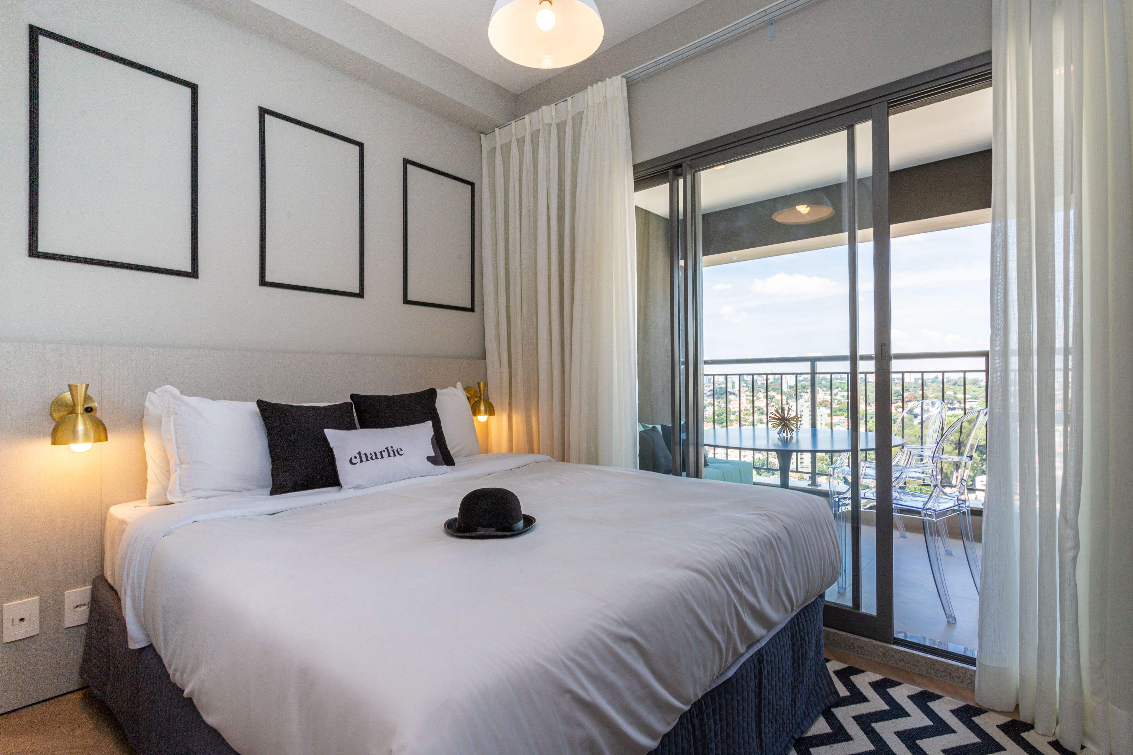 Habitación de hotel con una cama grande, un balcón con vistas y cuadros en la pared.