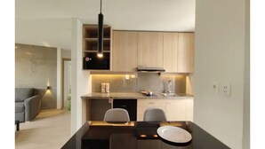 A modern kitchen with wooden cabinets, a black countertop, and a dining area with a black table and chairs.