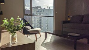 A modern living room with a large window, a sofa, a chair, and a coffee table.
