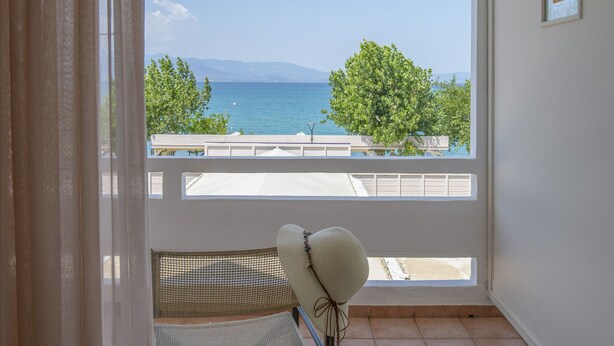A balcony with a view of the sea and mountains, a chair, and a small table with a lamp. - Hotel Kypreos Kamena Vourla (Kamena Vourla)