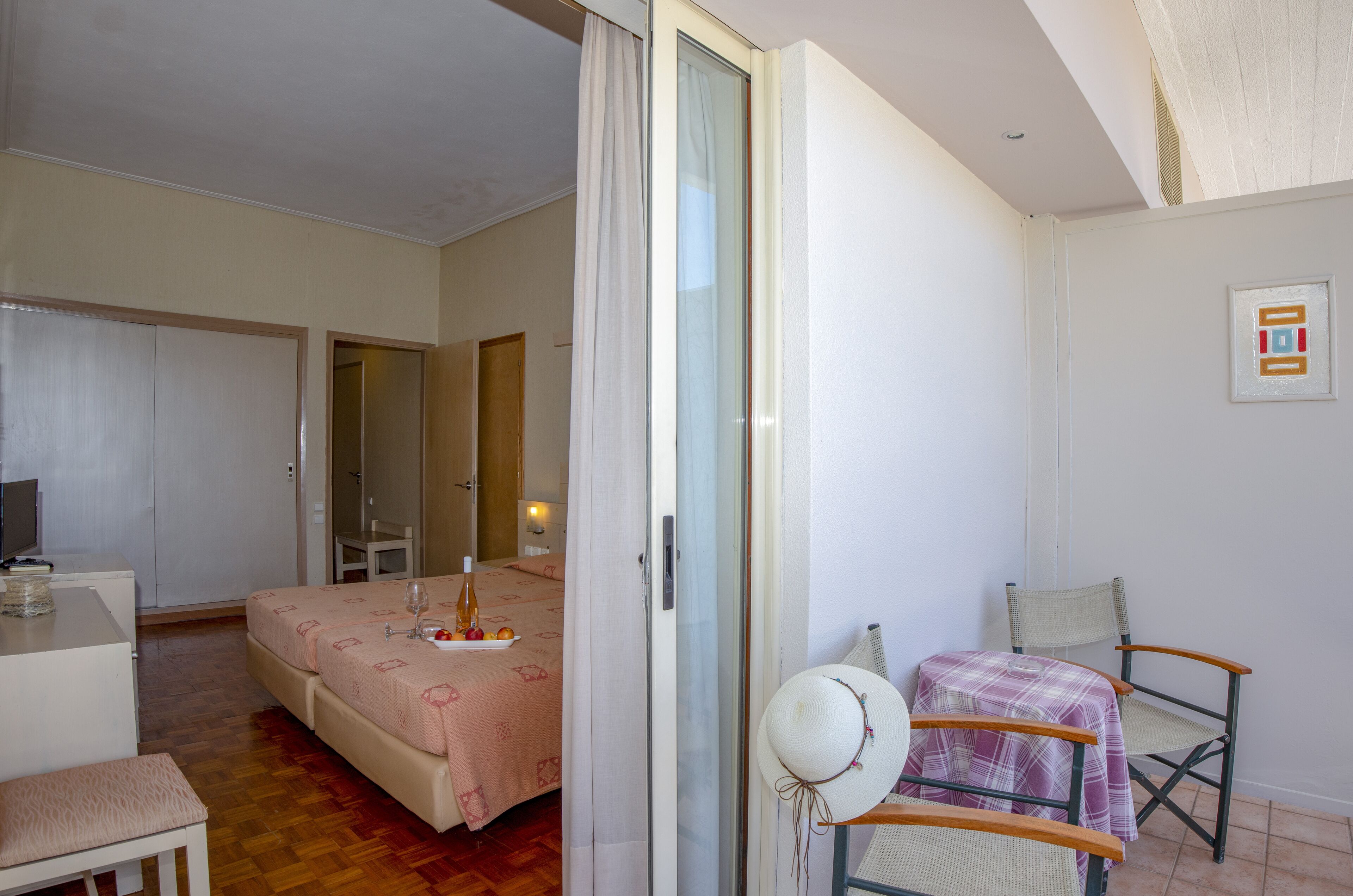 Une chambre à coucher avec un lit, un bureau, une chaise et une table sur laquelle se trouvent un chapeau et une bouteille.