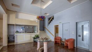 A spacious lobby with a marble floor, a glass-top table with a decorative centerpiece, a staircase, and a red patterned chair. - Hotel Kypreos Kamena Vourla (Kamena Vourla)