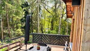 A wooden deck with a table and chairs, surrounded by trees. - Vacation home II Zittertal Neustadt Harz with large fenced garden (Neustadt/Harz)