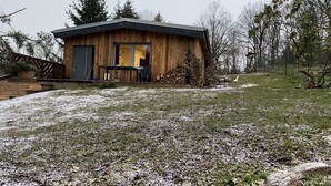 A wooden cabin with a large window, a door, and a small porch area. - Vacation home II Zittertal Neustadt Harz with large fenced garden (Neustadt/Harz)