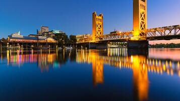 A bridge with two towers, a waterfront, and buildings in the background.