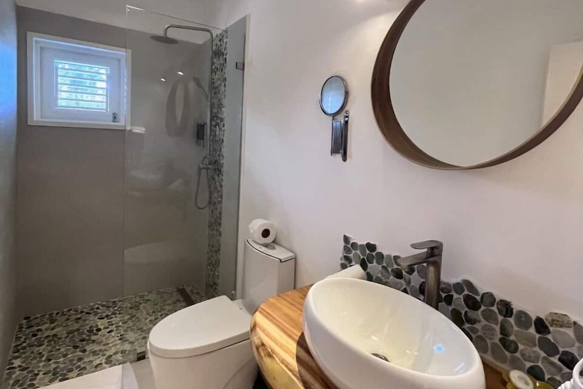 A modern bathroom with a large mirror, a wooden vanity, a bathtub, and a shower area.