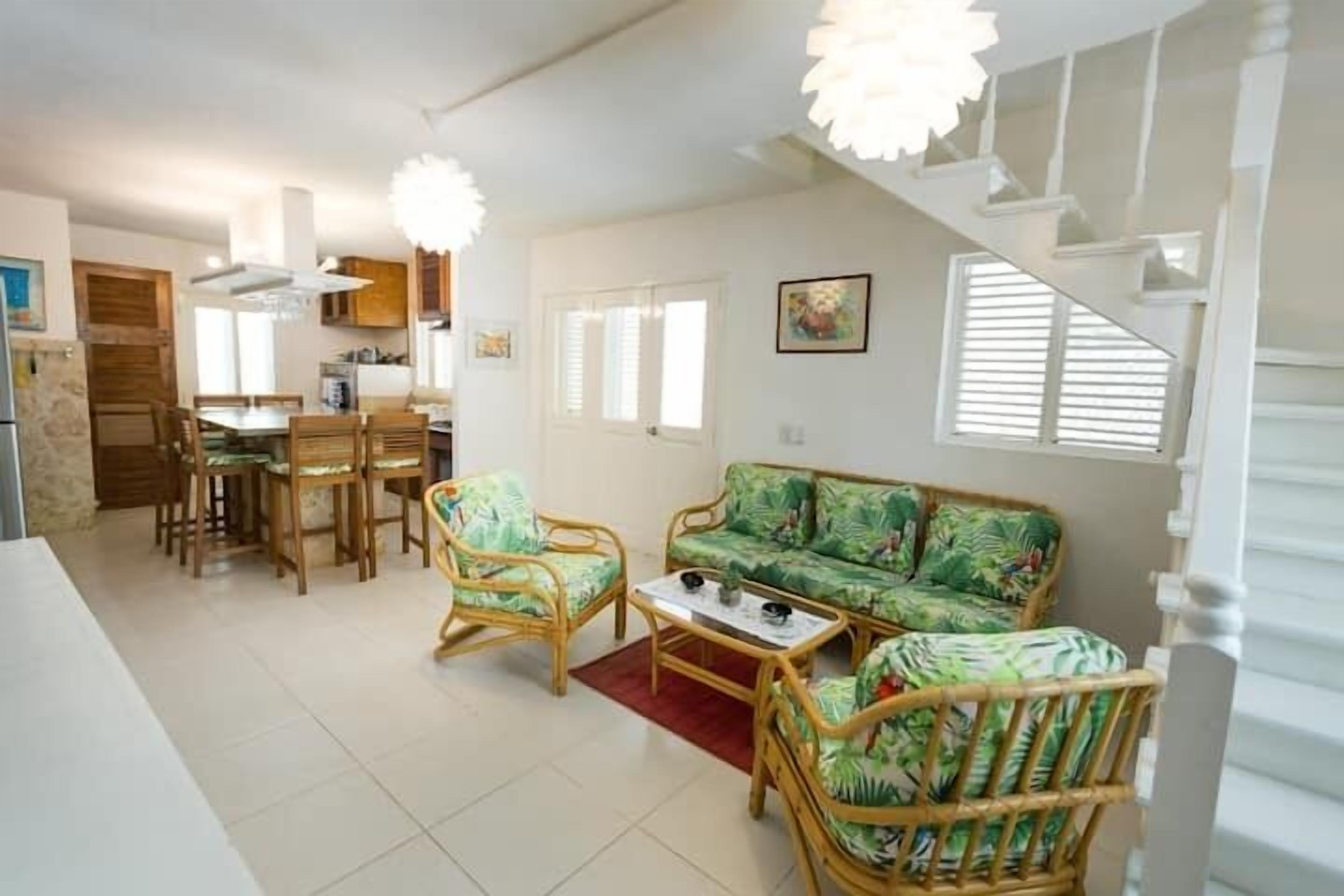 Amplia sala de estar con mesa de comedor, sillas, sofá y una escalera.