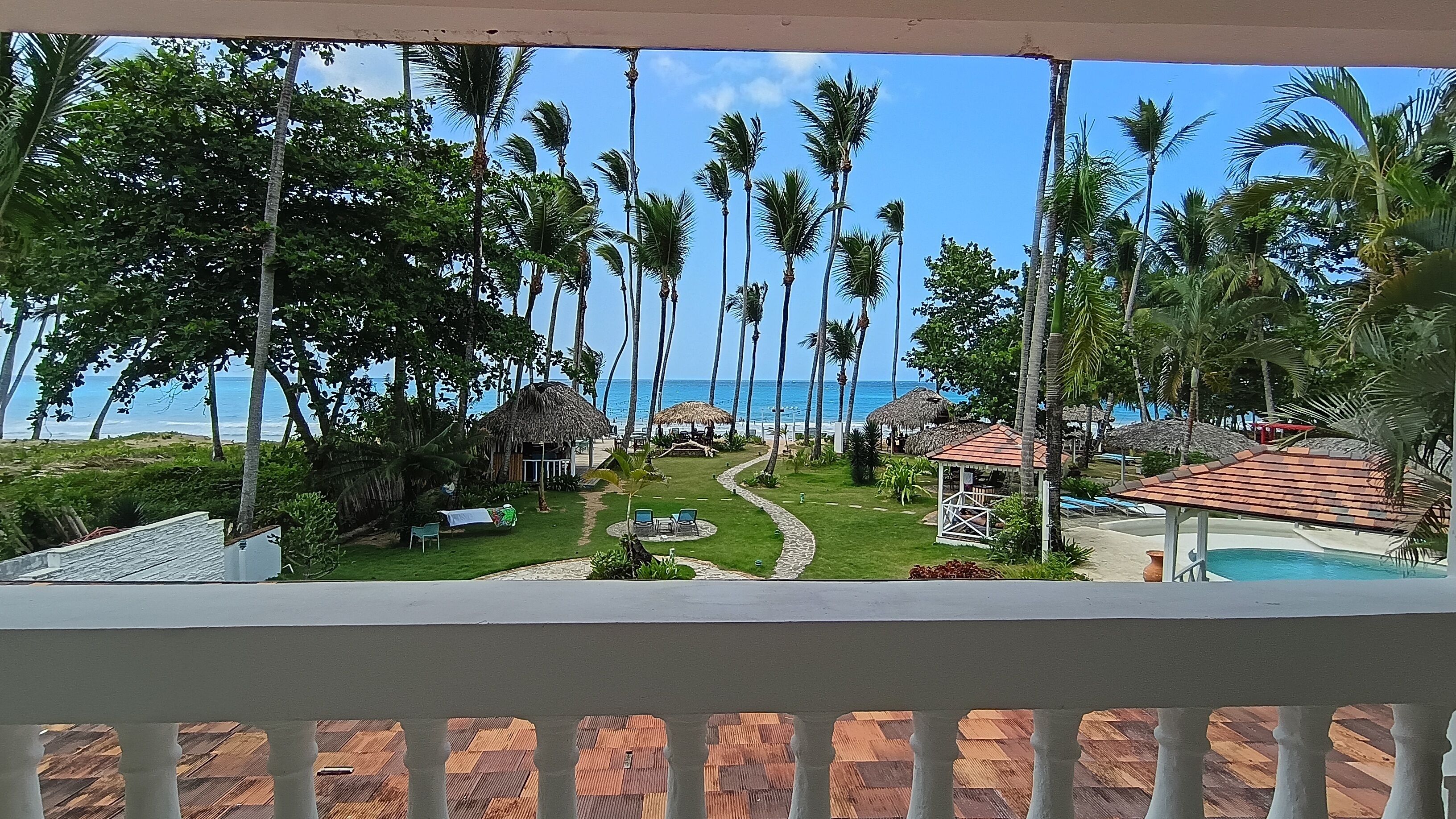 A resort with a pool, thatched-roof structures, and a view of the ocean.