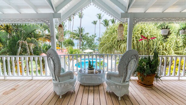 A covered outdoor area with two wicker chairs, a small table, and a potted plant. - Hotel Casa Coson (Las Terrenas)