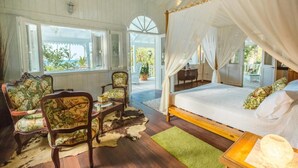 A bedroom with a four-poster bed, wooden flooring, and a view of the outdoors. - Hotel Casa Coson (Las Terrenas)