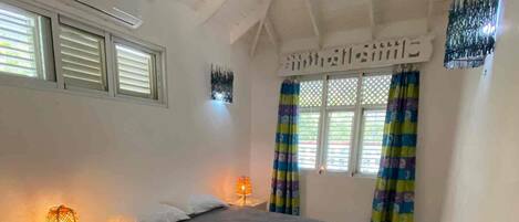 A bedroom with a bed, bedside lamps, a rug, and curtains.