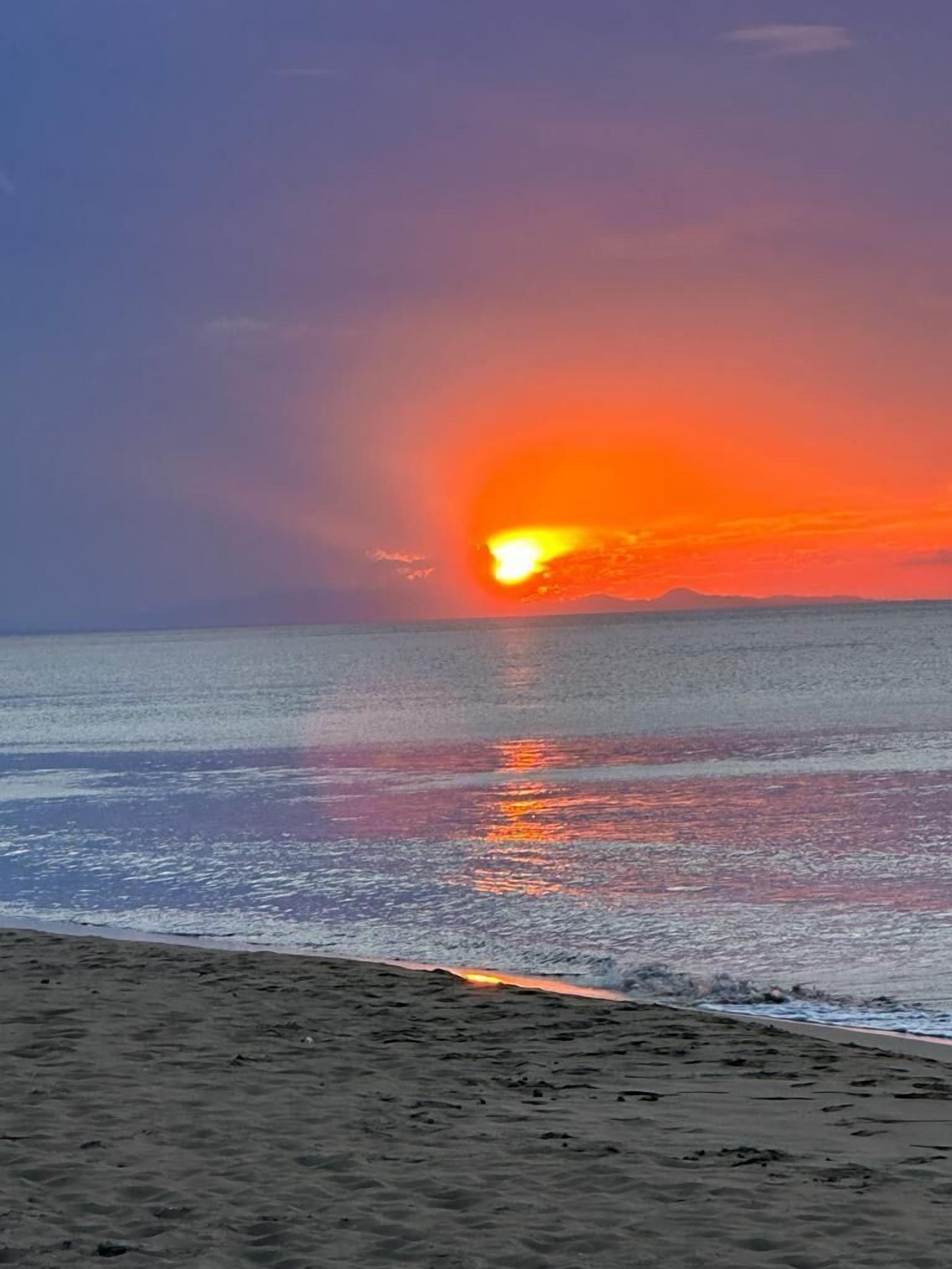 A beach with a sunset over the ocean.