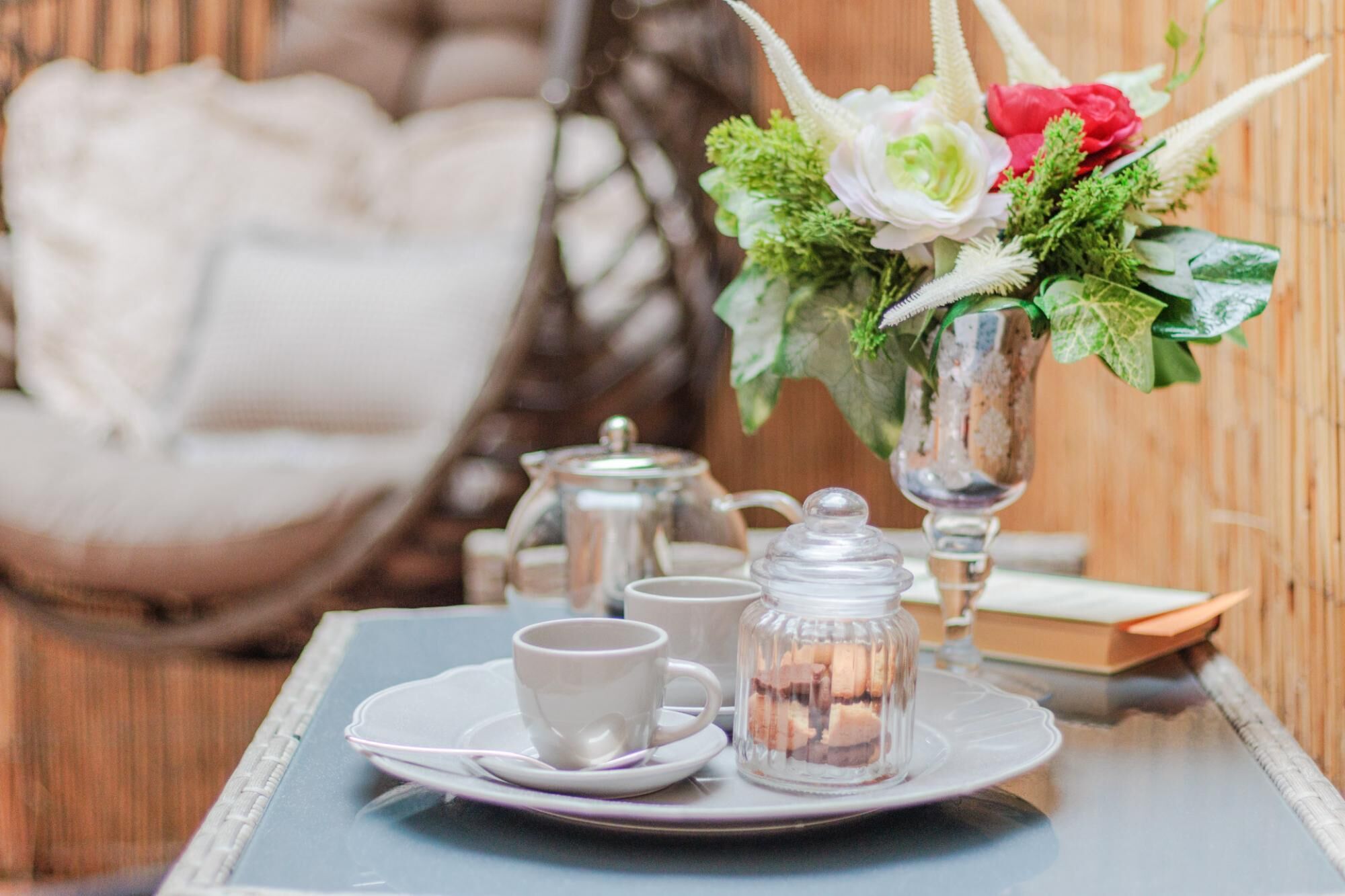 A tray with tea set and a floral arrangement on a table.