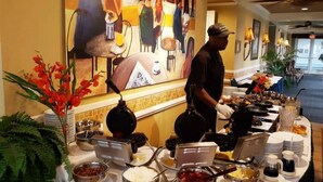 A buffet setup with various food items and a person serving.