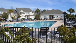 A swimming pool with lounge chairs and a fence.