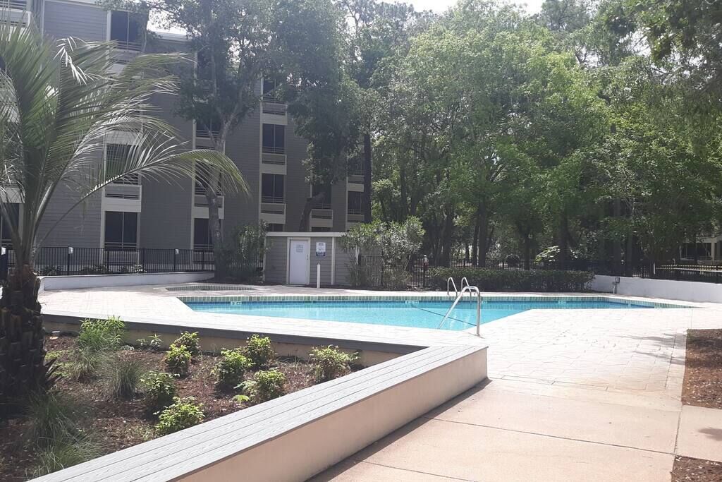 Une piscine entourée d’un espace paysager, avec un bâtiment en arrière-plan.