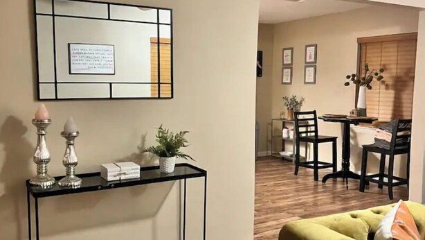 A living room with a sofa, a console table with decorative items, a dining area with chairs, and a kitchen in the background. - NEW 39th Street hot tub (Oklahoma City)
