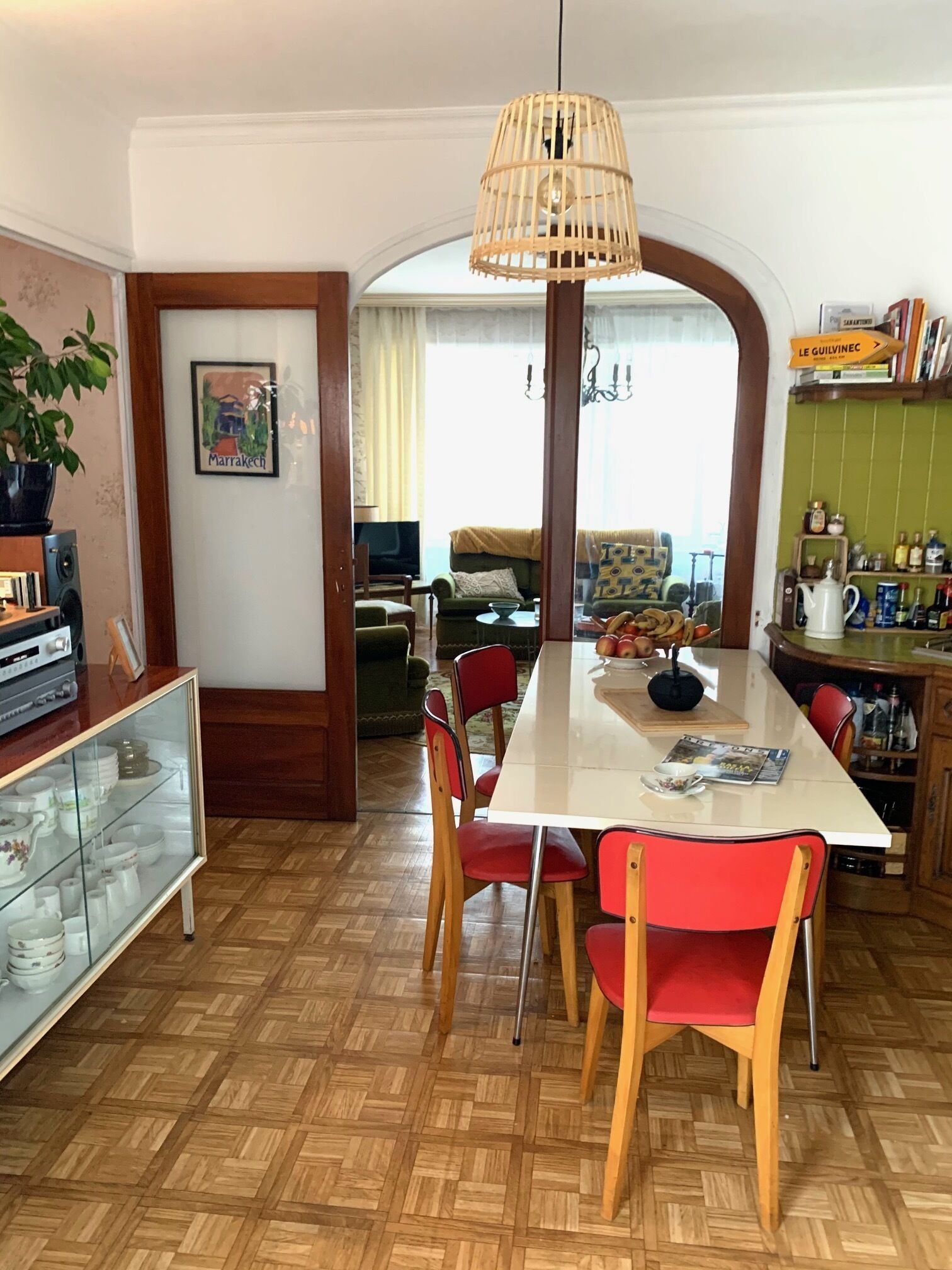 Un comedor con una mesa de madera, sillas rojas y una lámpara colgante.