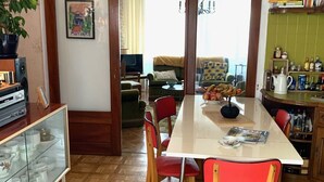 A dining area with a wooden table, red chairs, and a hanging light fixture. - Family home with large games room, close to the sea (Guilvinec)