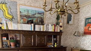 A living room with a wooden cabinet, two white chairs, a green sofa, and a patterned rug. - Family home with large games room, close to the sea (Guilvinec)