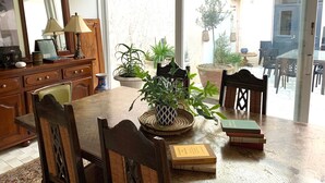 A dining area with a wooden table, wicker chairs, and potted plants. - Family home with large games room, close to the sea (Guilvinec)