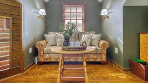 A cozy room with a brown leather sofa, a small round table, and a window with blinds. - Baladerry Inn (Gettysburg)