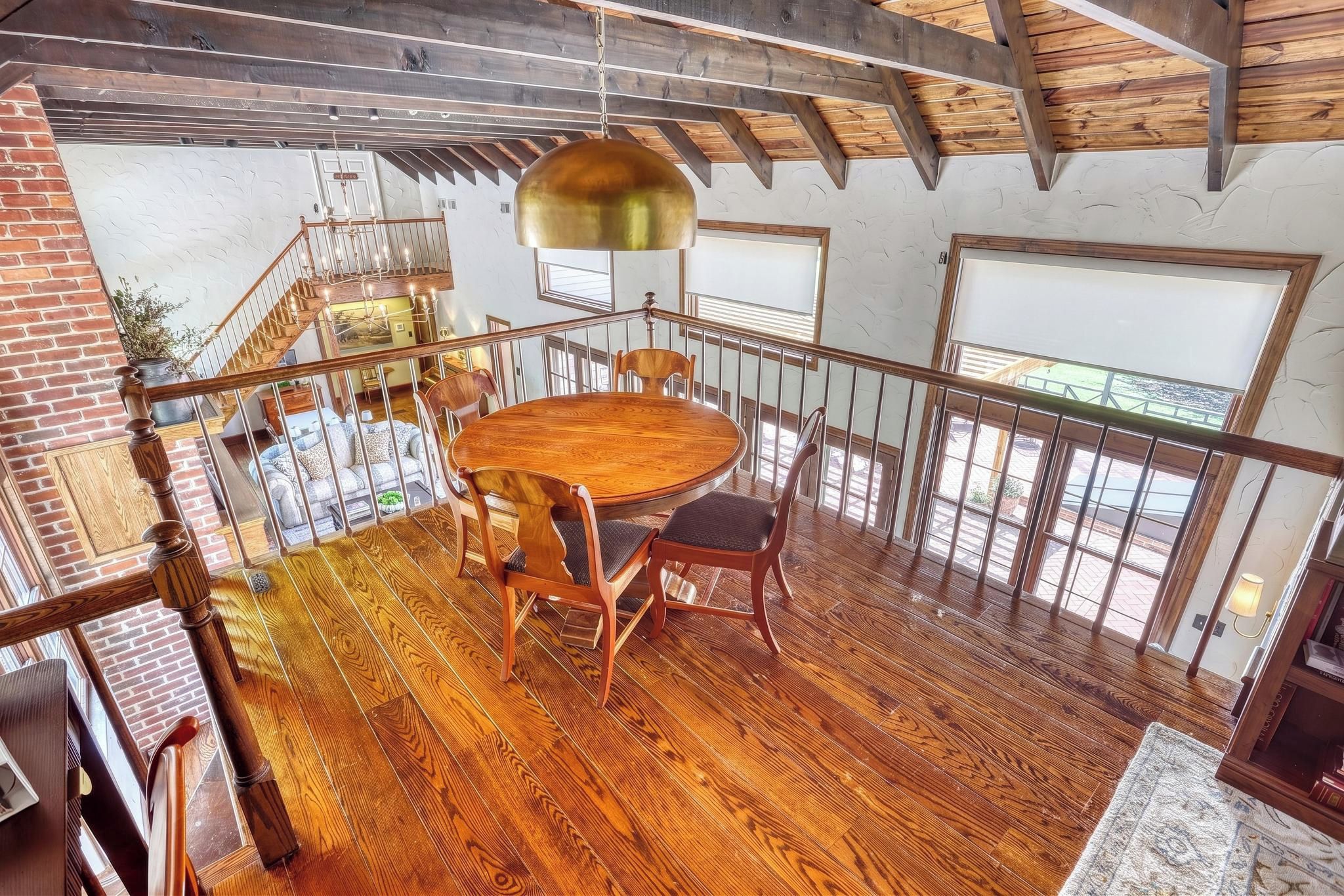 A wooden dining table with chairs in a room with a high ceiling and exposed beams.