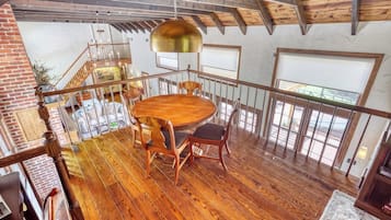 Una mesa de comedor de madera con sillas en una habitación con techo alto y vigas a la vista.
