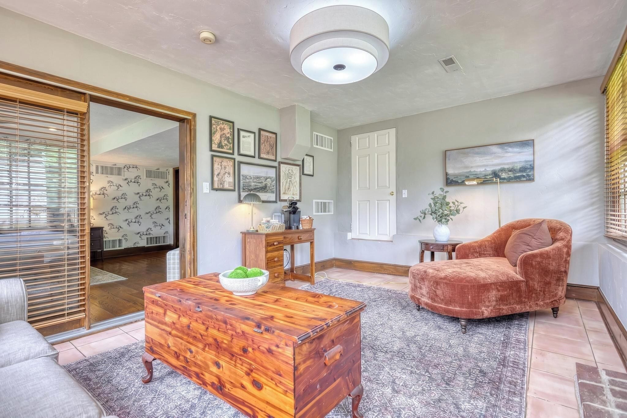 A living room with a wooden coffee table, a cushioned armchair, and a fireplace.