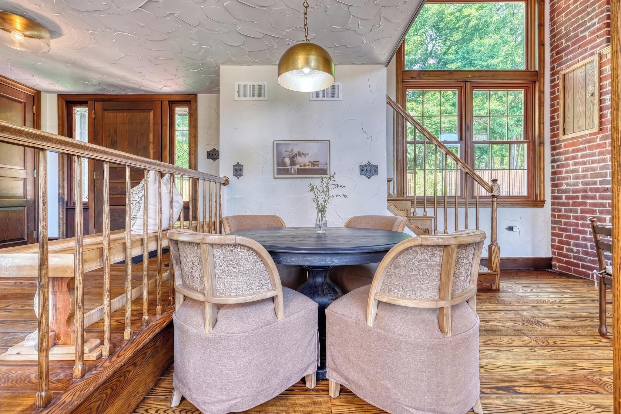 A dining area with a wooden staircase, a round table, and two cushioned chairs.