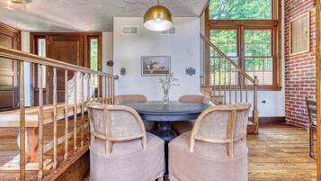 A dining area with a wooden staircase, a round table, and two cushioned chairs.