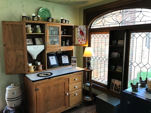 A kitchen with wooden cabinets, a coffee maker, and a window with a view of chickens outside. - Baladerry Inn (Gettysburg)