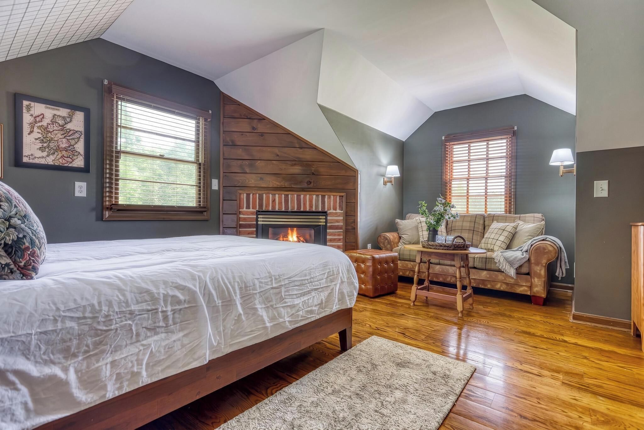 A bedroom with a bed, a fireplace, a sofa, and a dining table.