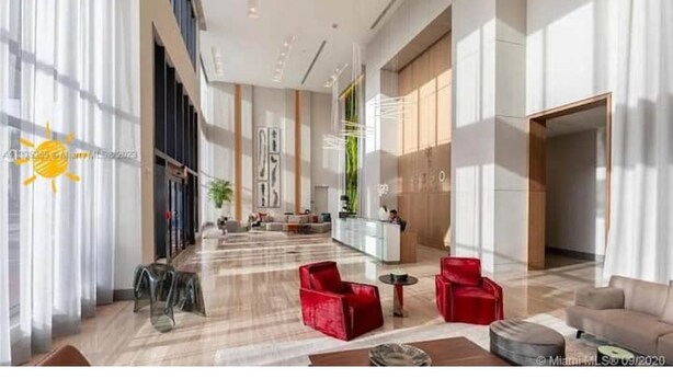 A spacious lobby with a reception desk, seating areas, and large windows allowing natural light. - Studio Unit at Downtown Doral (Doral)