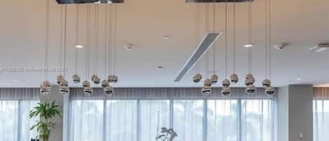 Una sala de estar moderna con un sofá, sillas naranjas y lámparas esféricas colgantes.