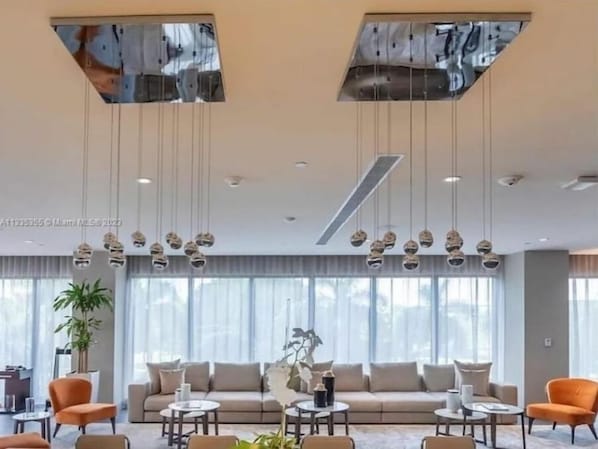 Uma sala de estar moderna com sofá, poltronas laranjas e luminárias esféricas penduradas.