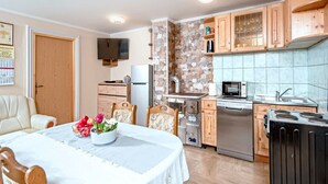 Cocina compacta con zona de comedor, destacando una pared de piedra, armarios de madera y electrodomésticos modernos.