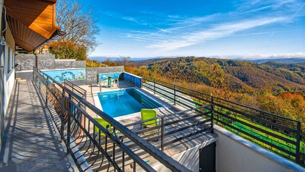 Una piscina en la azotea con vistas panorámicas de un valle boscoso.