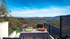 Una mesa al aire libre con mantel a cuadros, una botella y una cesta de fruta.