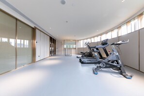 A modern gym with stationary bikes and a treadmill, large windows, and a clean, minimalist design.