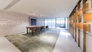 Una sala de conferencias moderna con una gran mesa, sillas y piso alfombrado.