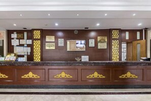 A reception desk with a marble top, framed certificates, and a digital screen. - Hequn Hotel (Xinchang)